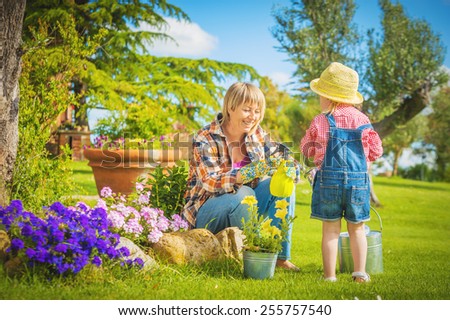 Beautiful little girl with a smile helps his mother in the work of gardening Beautiful little girl with a smile helps his mother in the work of gardening