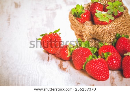 Spring fruits, strawberries in a linen sack on a vintage wooden table.