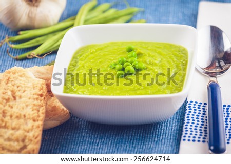 Green pea soup and bread on a blue tablecloth