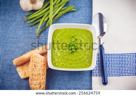 Green pea soup and bread on a blue tablecloth