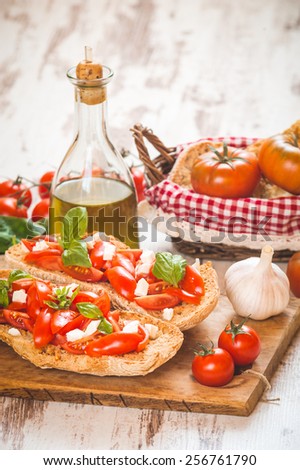 Italian starter, bruschetta with Sicilian red fresh tomato and mozerella cheese on a wooden background