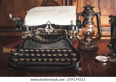 vintage photography still life with typewriter, folding camera, globe map and book on a wood table.