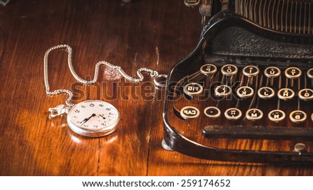 Old fashion pocket watch lying on the machine on a wooden table