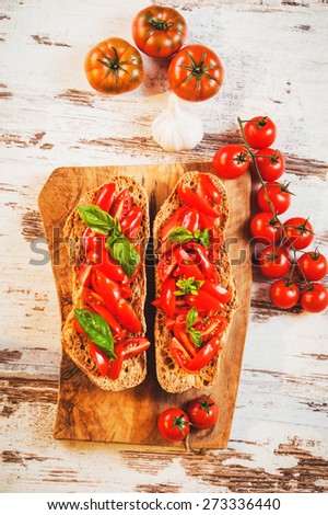 Italian starter, bruschetta with Sicilian red fresh tomato on a wooden background