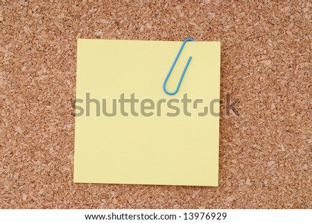 Yellow Note Paper With Paperclip On Cork Surface