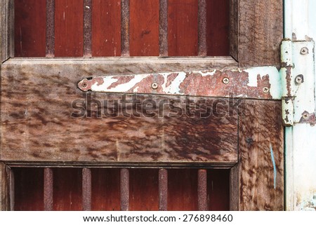 A fragment of an old door with a rusty door hinge.