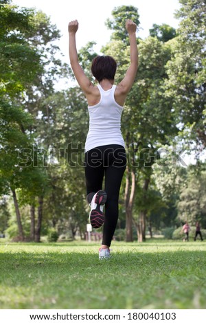 Woman raising arms for motivation before running in park.