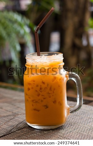 Iced Milk Tea with straw on a wooden table.