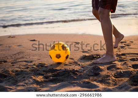 A guy playing football on the beach at sunset legs closeup