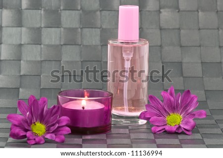 Spa candle, fragrance bottle and flowers on grey background