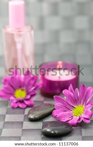 Spa stones, flowers, candle and fragrance bottle on grey background