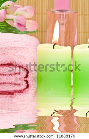 Spa candles, fragrance bottle, towel and decoration flowers with water reflection