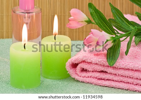 Spa candles, towel with decoration flower and fragrance bottle on bamboo background