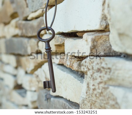 rusty old key hanging on the stone wall