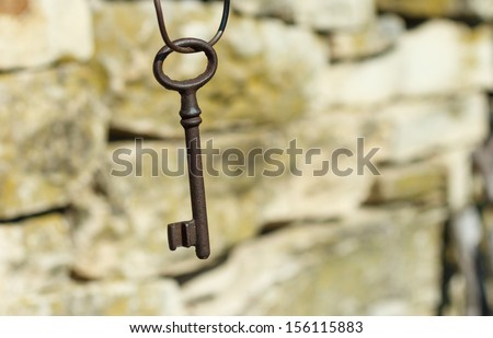 old key hanging on a stone wall background
