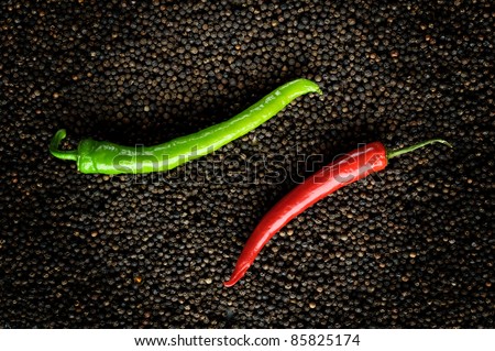 closeup green and red peppers on black peppercorns