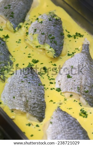 cooked fish fillets with yellow creamy sauce with parsley