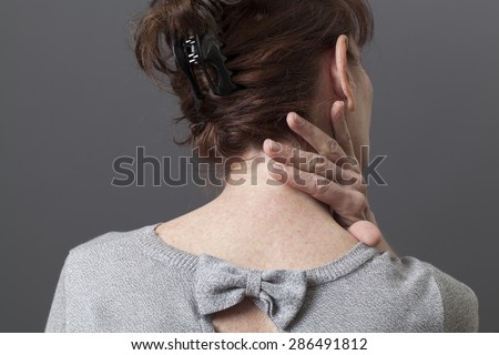 50s woman in back view with fatigue and tension in body