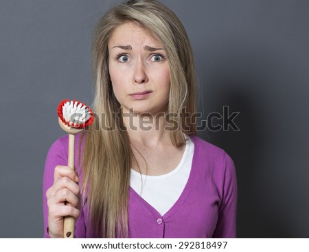 embarrassed young blond woman handing dish brush for question about washing dishes