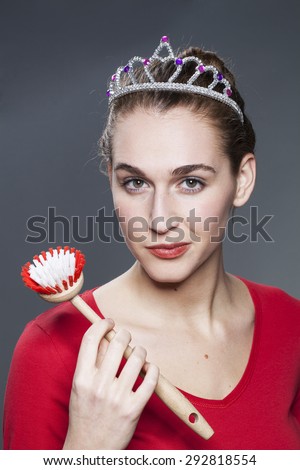 smiling young gorgeous woman wearing princess tiara with dish brush in hand for housekeeping queen or cleaning house master