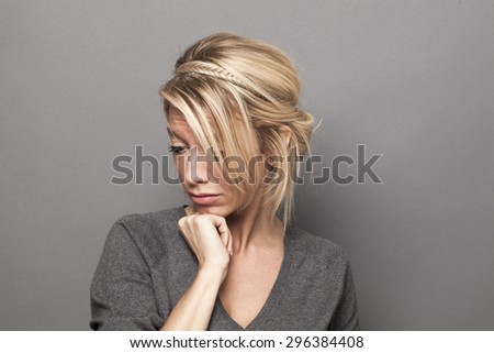 thinking 30\'s sophisticated blonde girl, looking depressed with seasonal affective disorder syndrome, studio shot