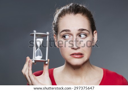 nervous beautiful young woman holding egg timer for concept of time management