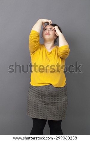 young fat girl with brown hair and yellow sweater scratching her head for creativity and fun reflection