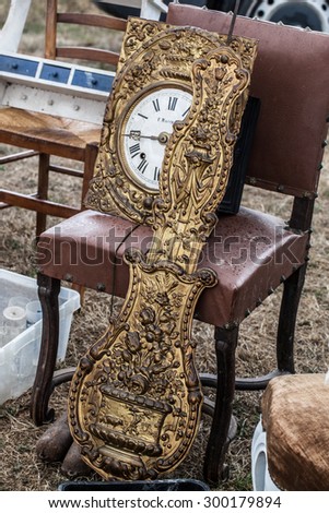 display of old clock parts in brass and rustic chairs sold at flea market for antique and vintage collections