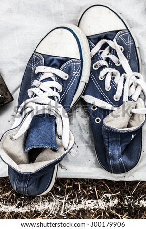 second hand fabric navy blue sneakers on sale at garage sale on grass for donation, recycling or selling for cheap to cope with over-consumption and fashion