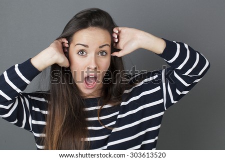 surprise and success concept - attractive 20s woman putting both hands on her face shouting for surprise and happiness