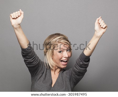 success concept - sexy young blonde woman winning a competition with fun body language and hands up above