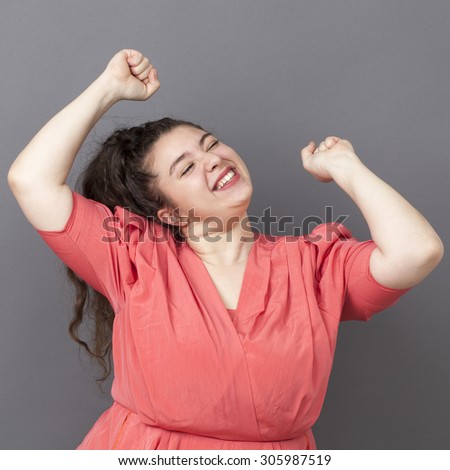 success concept - smiling young overweight girl wearing a vintage dress dancing expressing her achievement and happiness