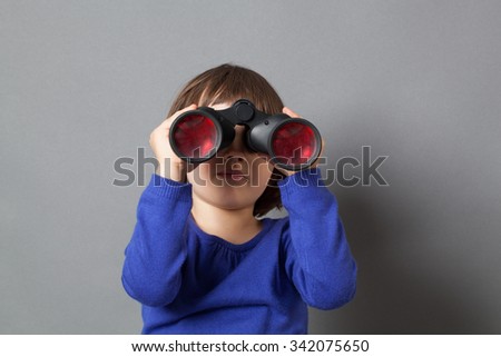 kid exploration concept - focused 4-year old child with bob cut in watching through binoculars for discovery and imagination,studio shot