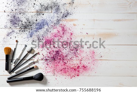 Wallpaper for professional makeup and fashion accessories with blush and eyeshadow brushes with smashed colorful pigments, white wooden background, copy space, above view