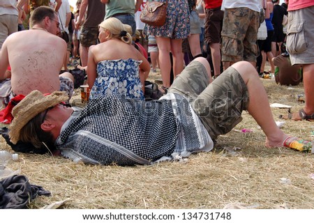 GLASTONBURY,UK - JUNE 27: A festival goer takes a rest as a crowd of music fans gather by the Pyramid Stage at  Glastonbury Festival on 27th June, 2010 at Pilton Farm, Somerset.