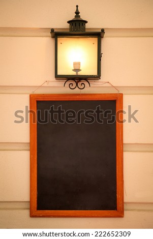 Blank Blackboard and lamp on a wall background