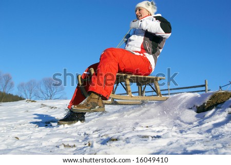 sports girl on sledge climbs down a mountain