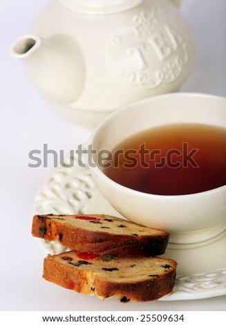 Cup of tea with cake and teapot in the background