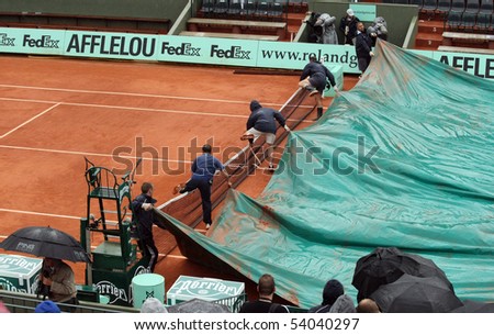 PARIS - MAY 27: Ground staff pull covers over courts due to rain at French Open, Roland Garros on May 27, 2010 in Paris, France.