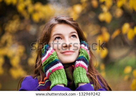 Autumn portrait of lovely young woman with mittens near face in forest
