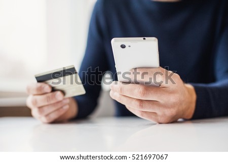 Male hands holding credit card and using smart phone. Online shopping concept