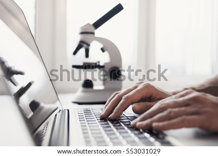 Scientist or student using  laptop computer and microscope