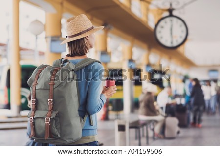 Young woman traveler waiting for a bus on a bus station, travel and active lifestyle concept