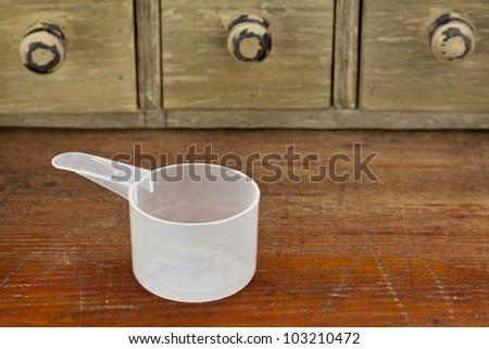 empty plastic measuring cup on a grunge wooden counter with drawer cabinet