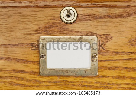 blank label in brass holder on a wooden file cabinet drawer with a lock