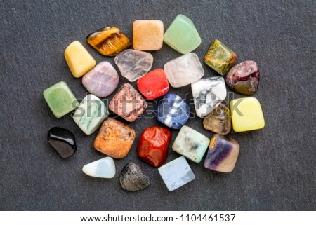a set of small, polished, semiprecious, colorful gemstones against gray slate stone