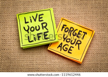 live your life, forget your age - inspirational handwriting on sticky notes against burlap canvas