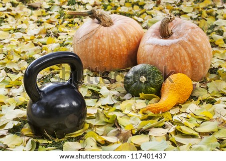 heavy iron  kettlebell outdoors in a fall scenery  with pumpkin and squash - outdoor fitness concept