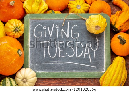 Giving Tuesday  - white chalk handwriting on a slate blackboard surrounded by winter squash and gourds