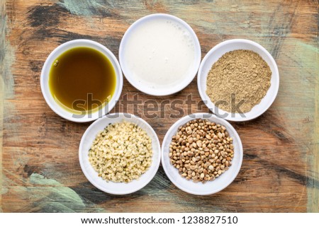 collection of hemp seed product:s hearts, protein powder, milk and oil in small white bowls against grunge wood